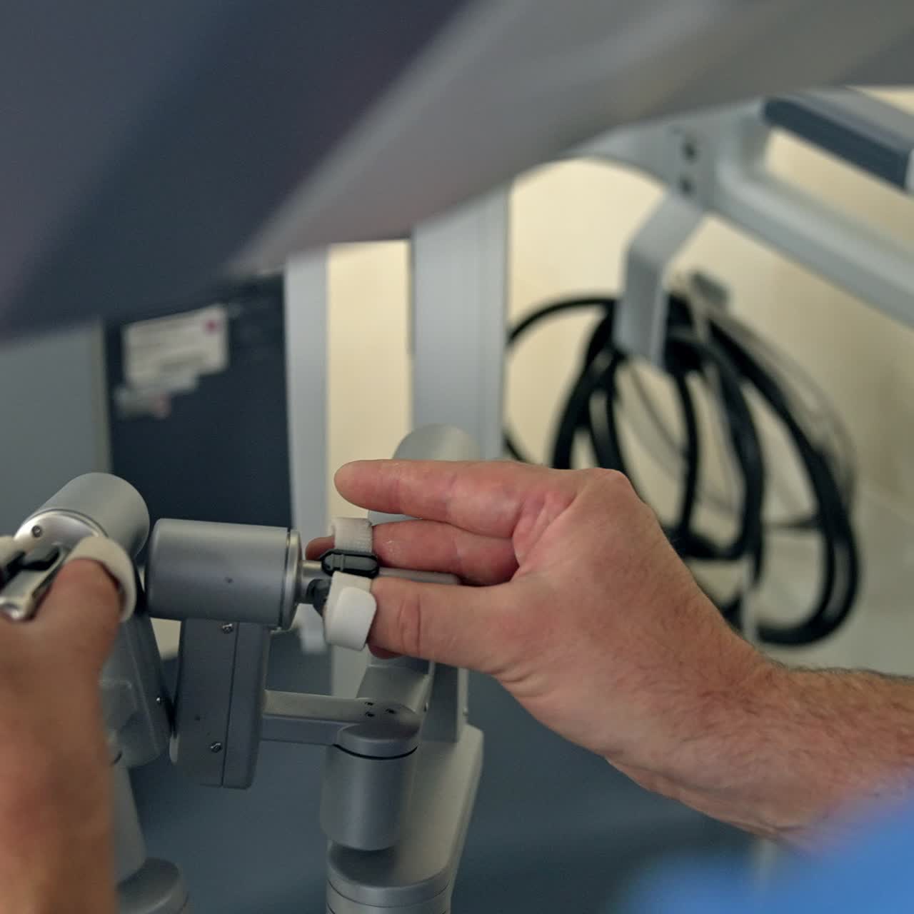 Medical specialist operating the modern futuristic equipment in surgery room. Male hands moving the handles of advanced apparatus. Close up