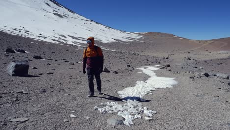 un excursionista masculino camina hacia la cámara en un remoto paisaje montañoso nevado