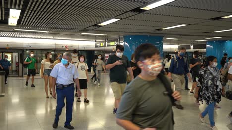 crowd of passengers in masks walking at admiralty train station in hong kong