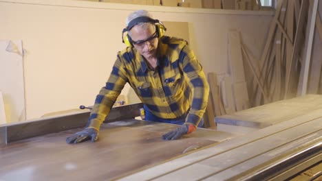 carpenter man is cutting wood in workshop.