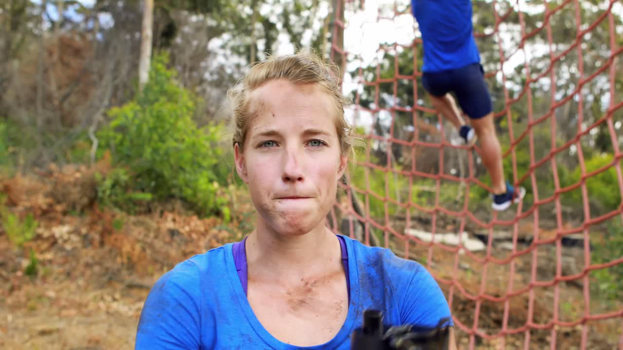 mujer en forma bebiendo agua después del entrenamiento durante una carrera de obstáculos
