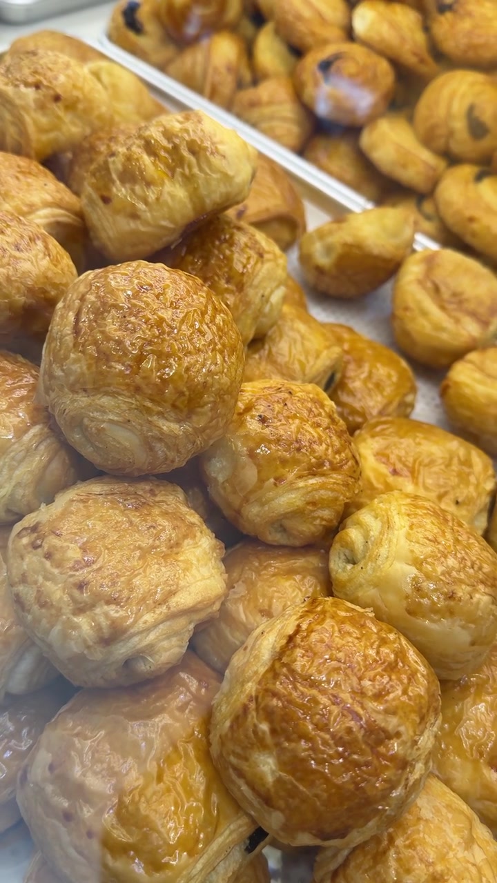 Primo piano di pain au chocolat dorati in una vetrina di pasticceria.