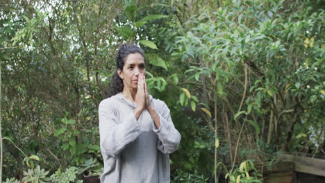 focused biracial woman practicing yoga in sunny garden, slow motion