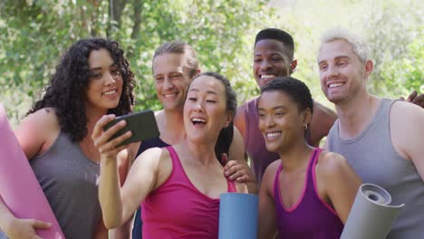 group of diverse young people holding yoga mats taking a selfie at the park