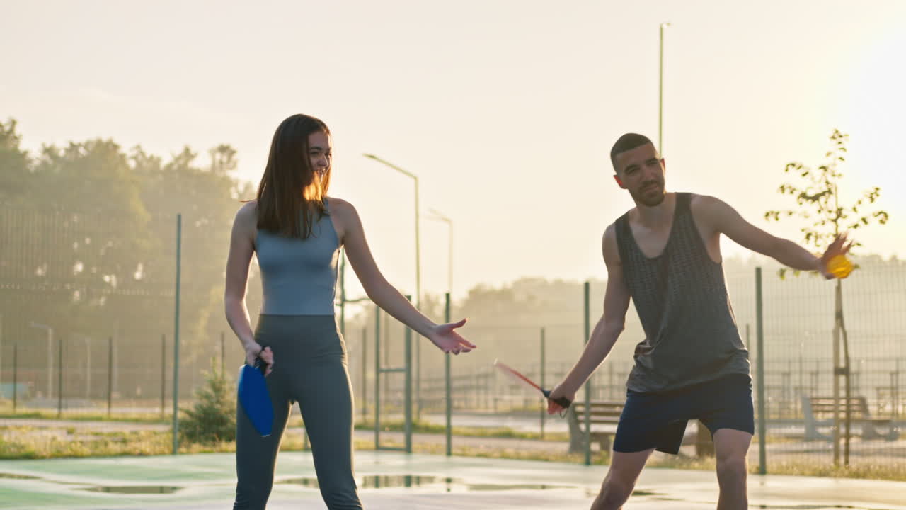 A man teaching a woman how to play pickleball after rain