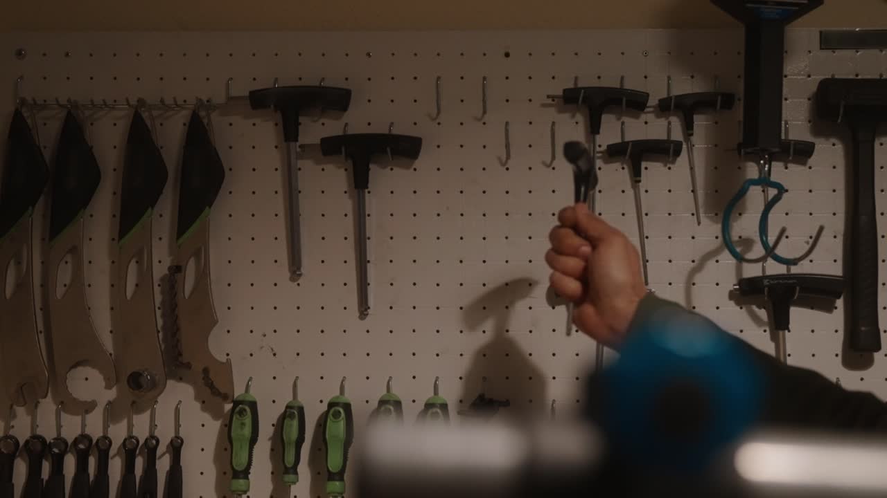 Various hand tools neatly organized on a pegboard wall in a workshop setting, hand taking tool