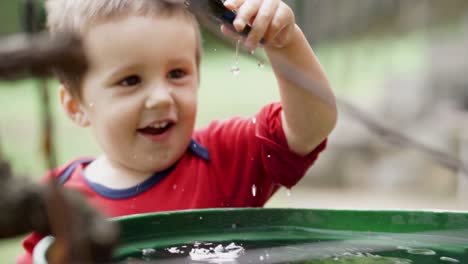 Niño-Blanco-Sonriente-Tirando-Un-Avión-De-Juguete-En-Un-Barril-Lleno-De-Agua,-Cámara-Lenta