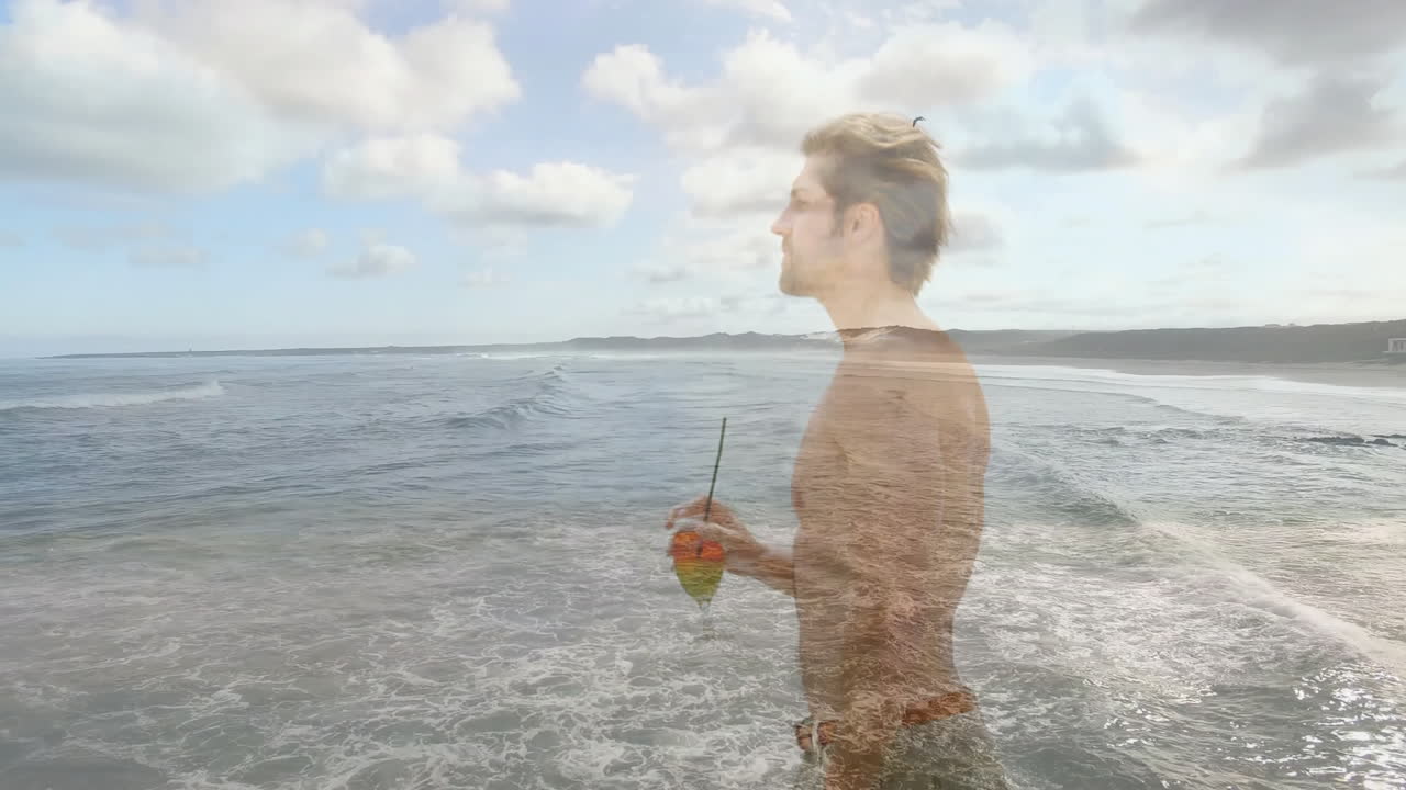 Holding drink, man overlaying on animation of ocean waves and cloudy sky