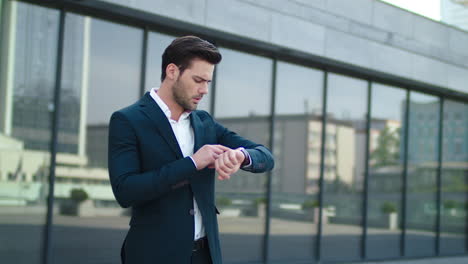 Closeup-man-standing-near-business-building.-Businessman-waiting-in-suit-outdoor