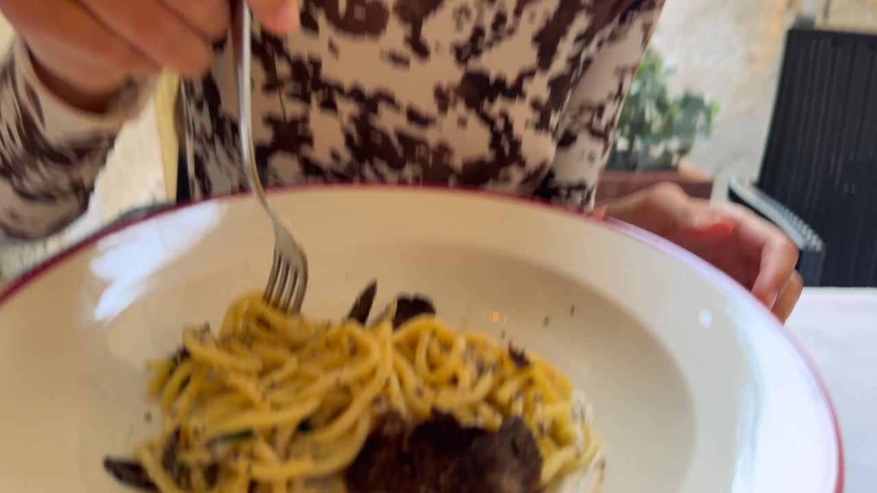 Primo piano di una persona che mangia deliziosi spaghetti con tartufo fresco.