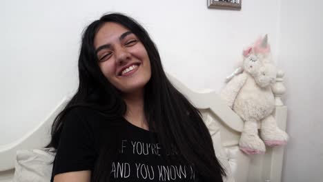 girl laughing while sitting on her bed