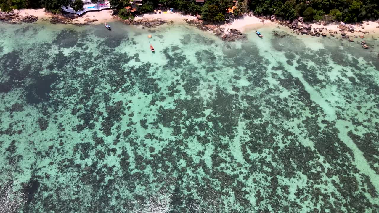 Ripresa aerea dall'alto su tranquille acque coralline verso la spiaggia a Koh Lipe