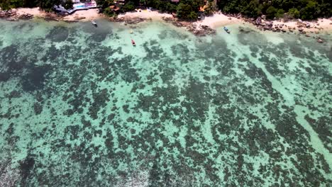 overhead aerial over tranquil coral waters towards beach at koh lipe