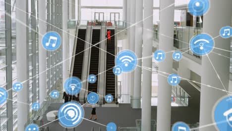 animación de una red de iconos digitales sobre una vista aérea de escaleras mecánicas en una oficina moderna