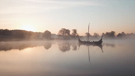 Drone-flying-over-lake-with-viking-ship-floating-in-the-middle