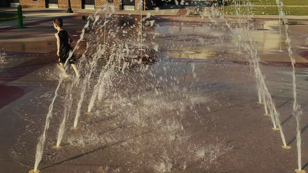Young Boy Running Through Water Tunnel at a Splash Pad