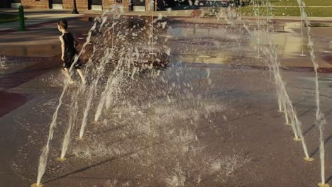 Kleiner-Junge,-Der-Durch-Einen-Wassertunnel-An-Einem-Spritzpad-Läuft