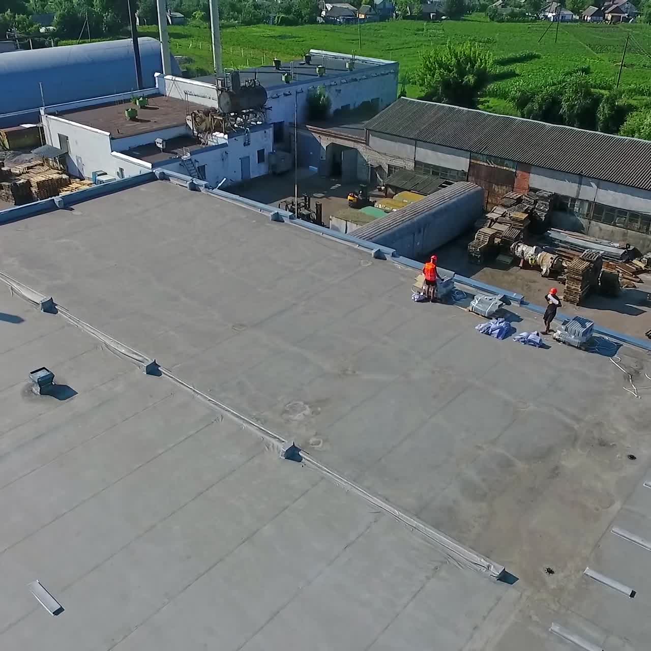 Construction on a rooftop. Building the solar farm on flat roof. Builders on construction site of future alternative power plant on the top of building. Aerial view.