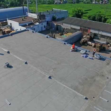 construction on a rooftop. building the solar farm on flat roof. builders on construction site of future alternative power plant on the top of building. aerial view.