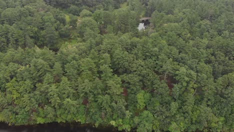 Río-Junto-A-Un-Pequeño-Puente-De-Un-Día-Nublado-Drone