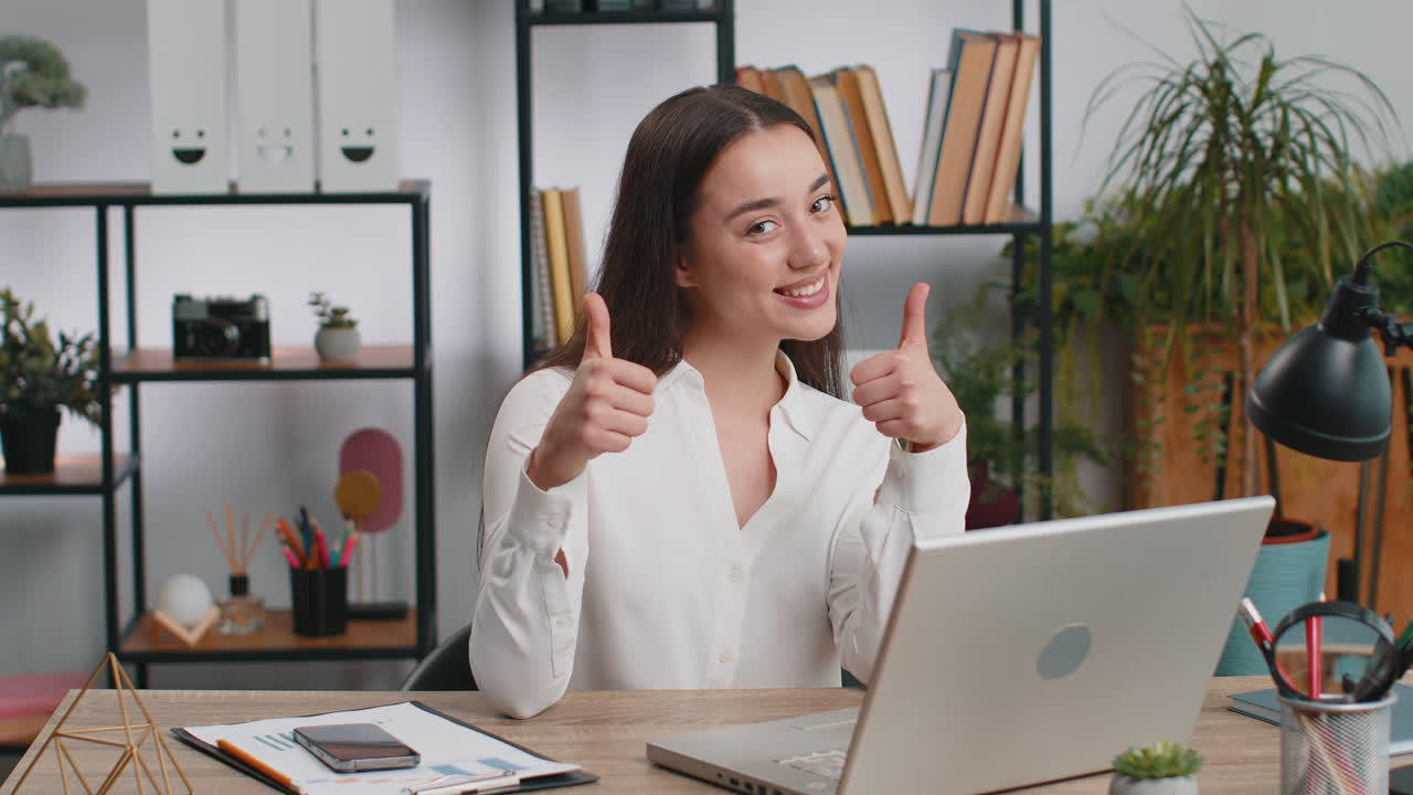 Happy business woman looking approvingly at camera showing thumbs up like positive sign good news