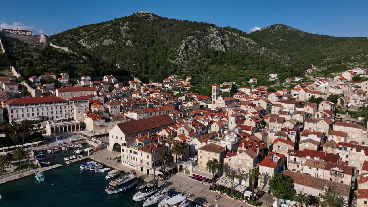 Aerial pull back shot of a town located in between hills at Hvar in Croatia. Nature landscape