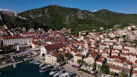 aerial pull back shot of a town located in between hills at hvar in croatia. nature landscape