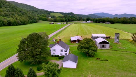 aerial push over farmhouse and farm in rural mountain city tennessee