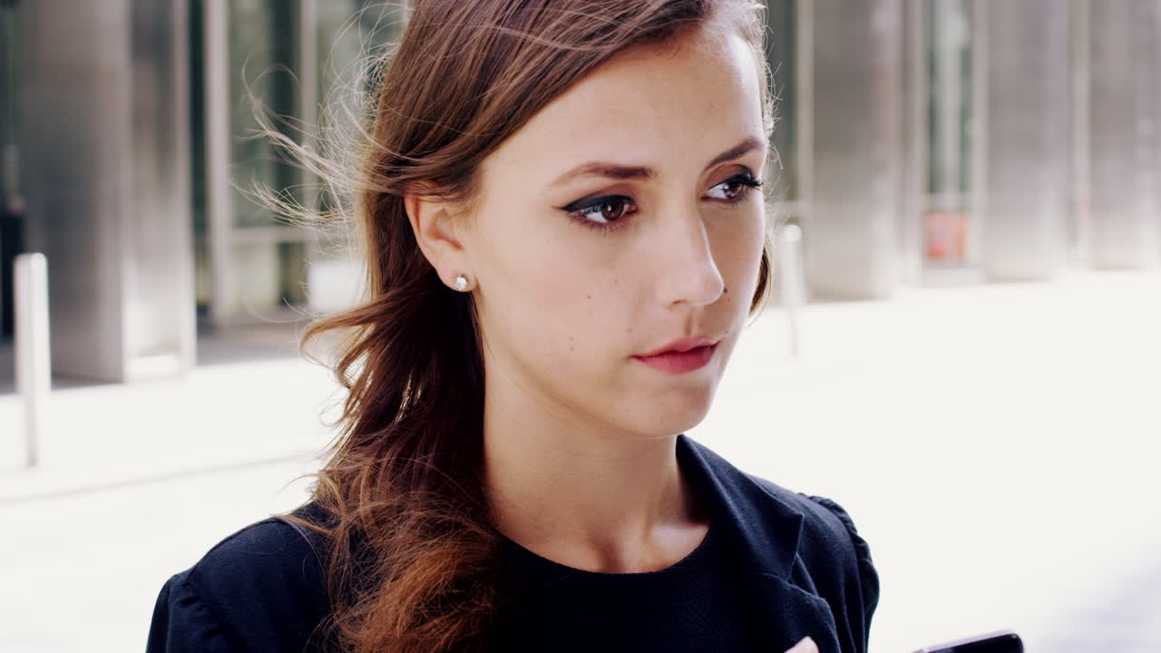 젊은 사업가 여성이 도시에서 전화를 보고 있습니다.