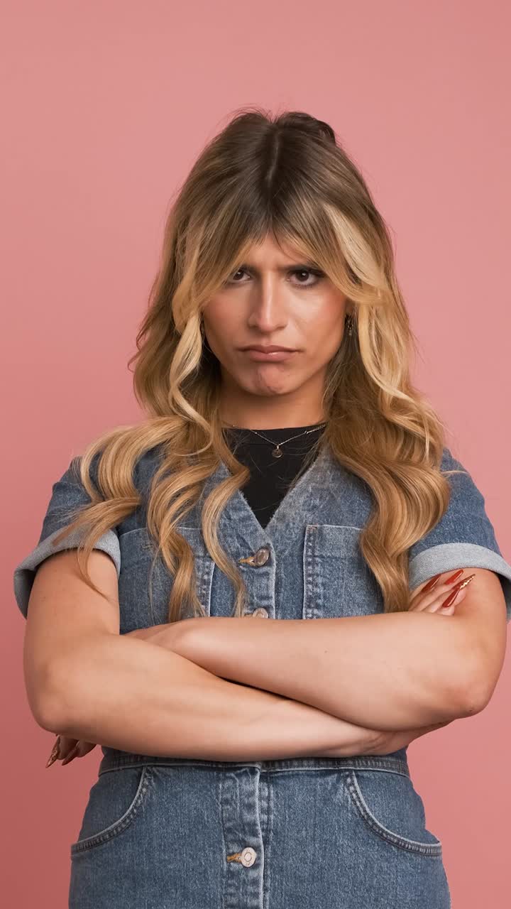 Angry transgender woman nodding head against pink background