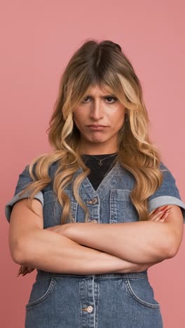 angry transgender woman nodding head against pink background