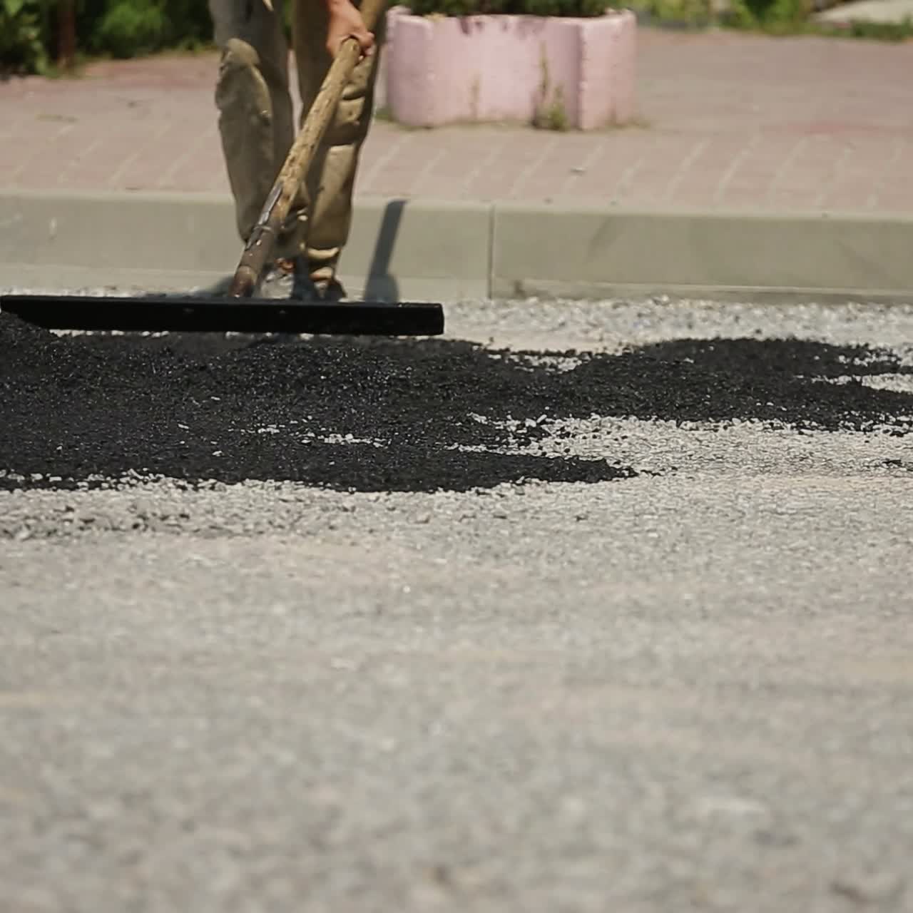 Worker Leveling Fresh Asphalt