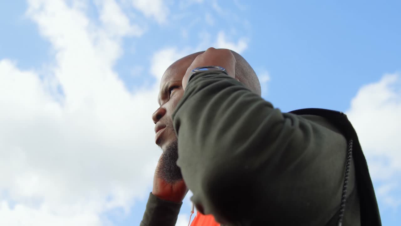 vista de bajo ángulo de un hombre escuchando música con auriculares en un día soleado 4k