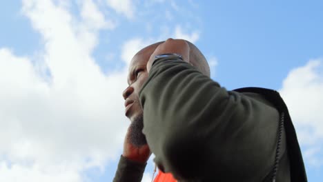 Low-angle-view-of-man-listening-music-with-earphone-on-a-sunny-day-4k