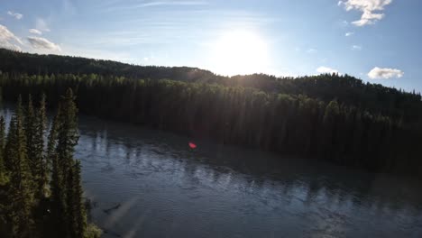 an fpv drone maneuvers over the treetops, gliding smoothly over the bow river in canada. captured in slow motion at 59.94fps, the shot reveals the vast forest below under a clear, sunny sky.