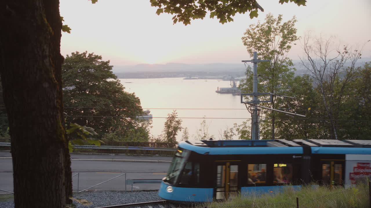 Trams pass on Kongsveien by Ekebergsparken in front of the setting sun