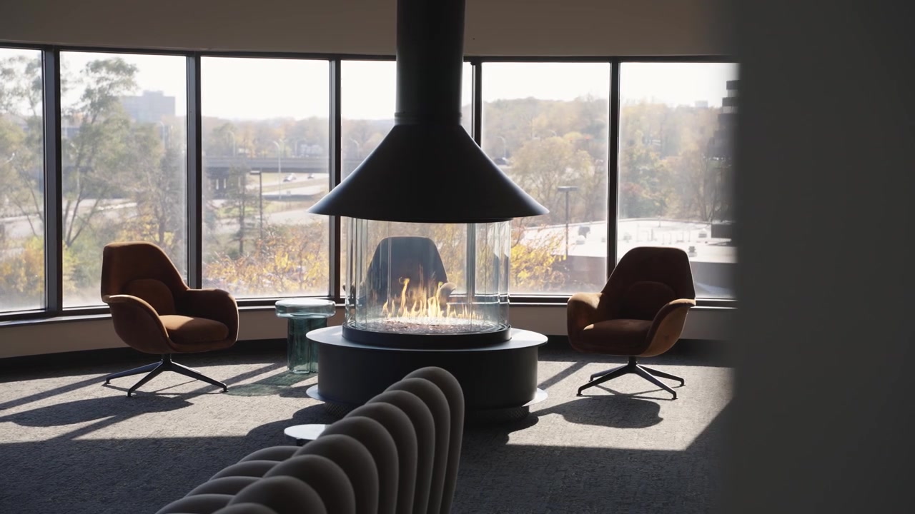 Stylish office lounge with chairs and fireplace overlooking the cityscape.