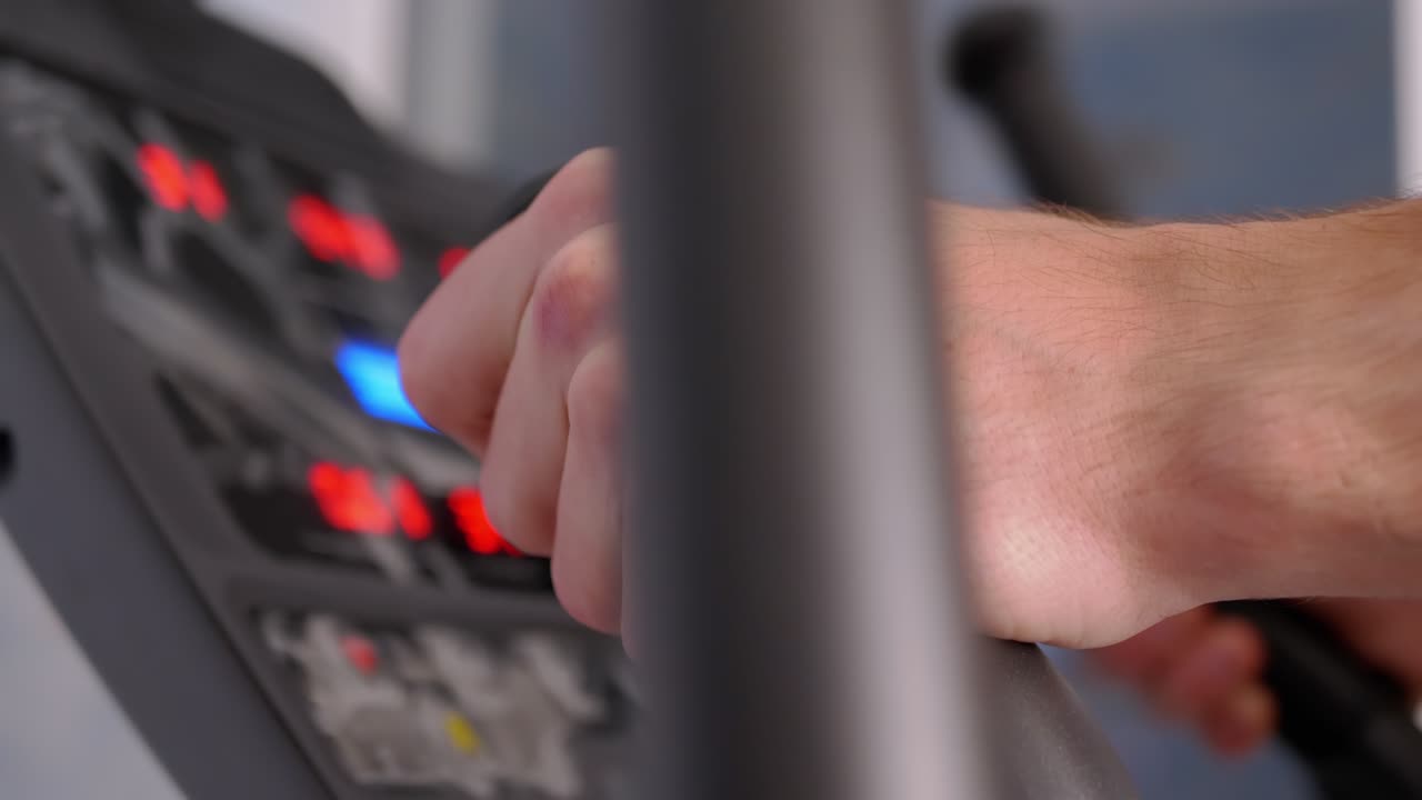 el atleta entrena en un entrenador elíptico en casa, observando el ritmo cardíaco en el monitor