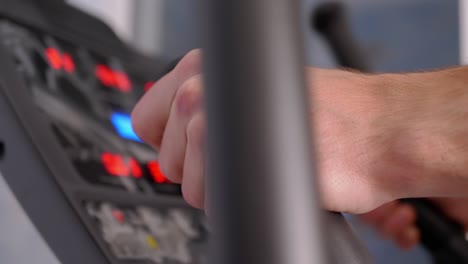 el atleta entrena en un entrenador elíptico en casa, observando el ritmo cardíaco en el monitor