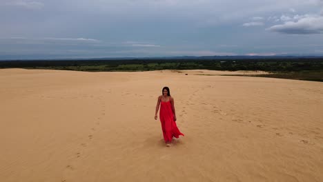 Bonita-Latina-Con-Cabello-Largo-Y-Oscuro-Y-Vestido-Largo-Rojo-En-Una-Enorme-Duna-De-Arena.