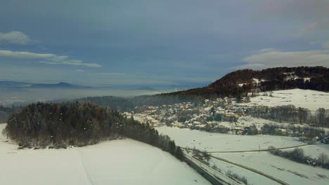 Aerial-shot-of-a-snow-covered-mountain-town-in-fog