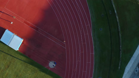 Vista-Aérea-De-Drones-4k-Del-Hombre-Corriendo-Vueltas-En-La-Pista-De-Carreras-Del-Campo-Deportivo,-Australia