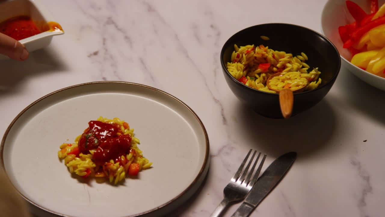 부에서 건강한 채식주의자 또는 채식주의자의 식사를 준비하는 여성, 오르조 파스타와 구운 토마토에 소스를 부어 1