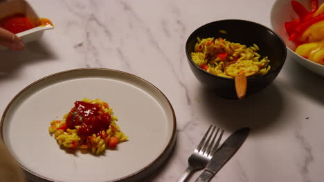 primer plano de una mujer en casa en la cocina preparando una comida saludable vegetariana o vegana vertiendo salsa sobre pasta de orzo y tomates asados 1