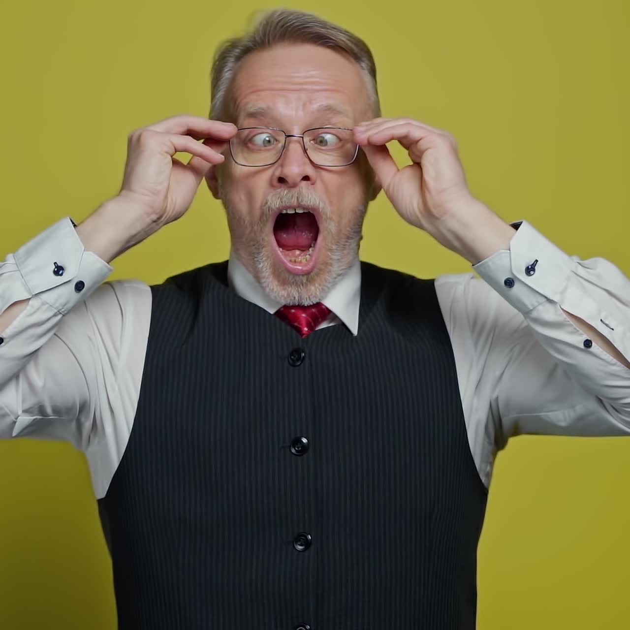 Funny mature man with glasses. Surprised male in elegant clothing putting on glasses. Terrified grandfather with opened mouth looking through his glasses. Slow motion.