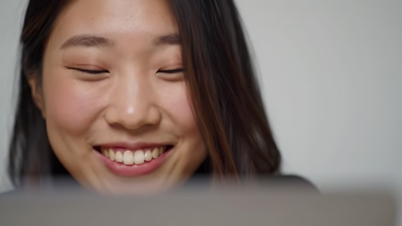 A Young Woman Engaged in a Joyful Conversation While Using Her Laptop, Capturing the Essence of Connection and Technology in a Bright Setting