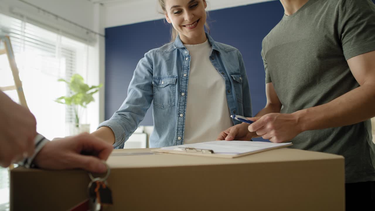 video de mano de una joven pareja firmando un acuerdo de compra de casa.