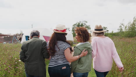 Rear-View-Of-Mature-Female-Friends-Walking-Along-Path-Through-Yurt-Campsite