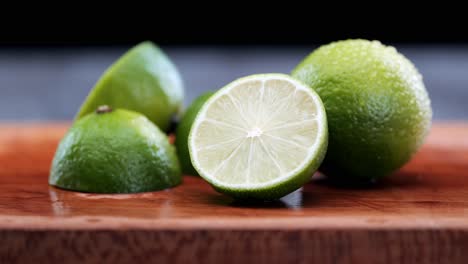 Lima-Limón-Verde-Recién-Cortada-Sobre-Una-Tabla-De-Cortar-De-Madera,-Ingredientes-Para-Un-Cóctel,-Alimentación-Agria-Y-Saludable