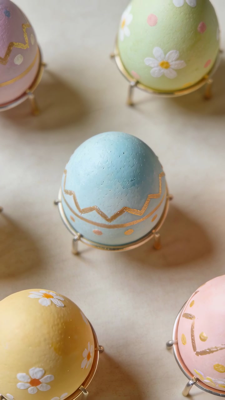 Vertical video: Panning camera revealing blue egg on light table with gold dots, showing detail